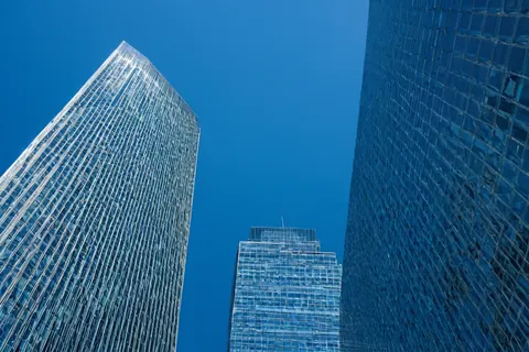 Three modern glass skyscrapers towering against a clear blue sky